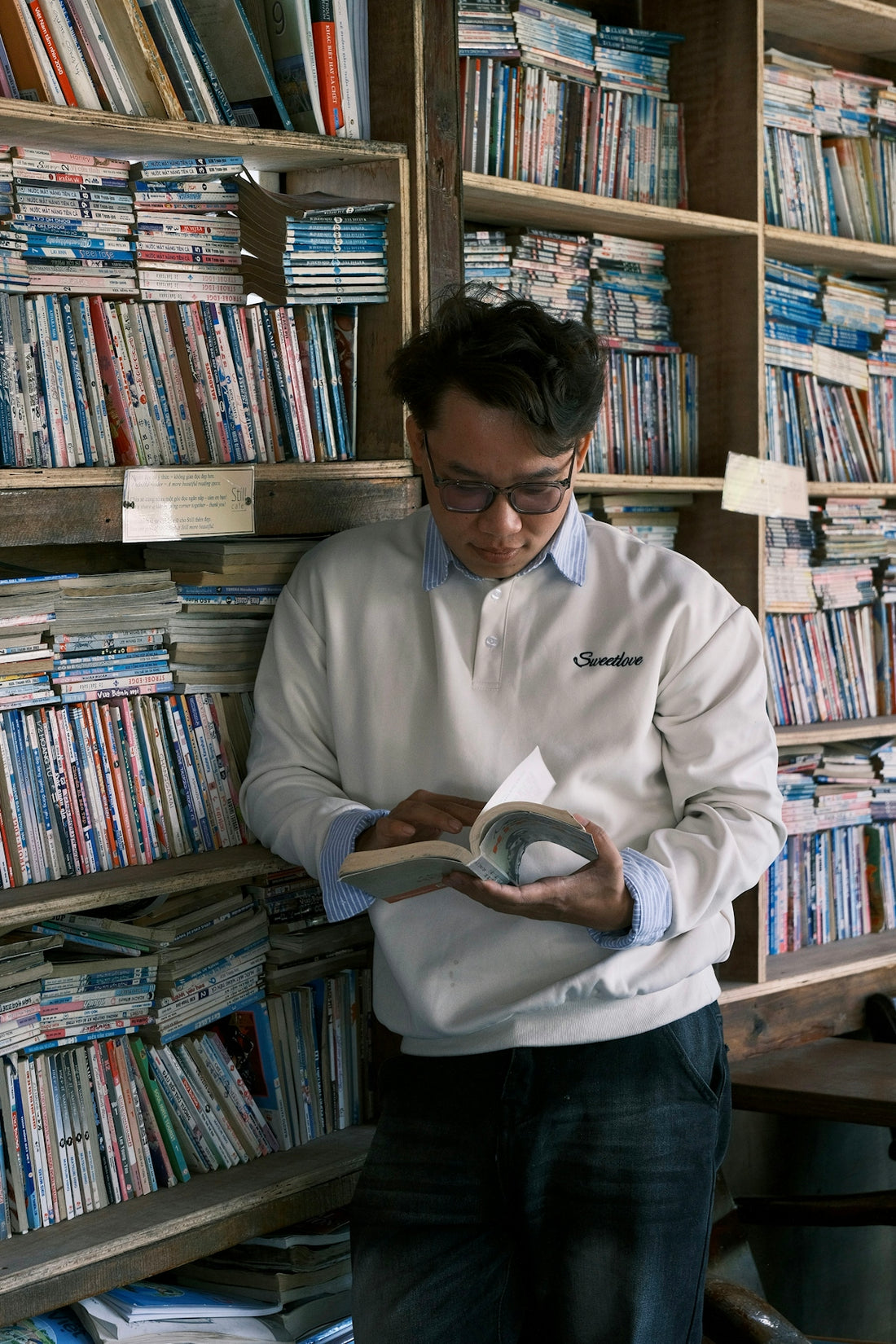 Man reading a book surrounded by bookshelves