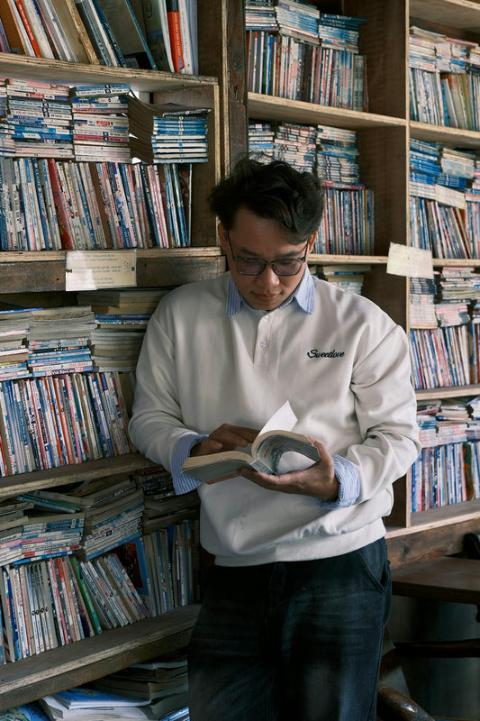 Man reading a book surrounded by bookshelves